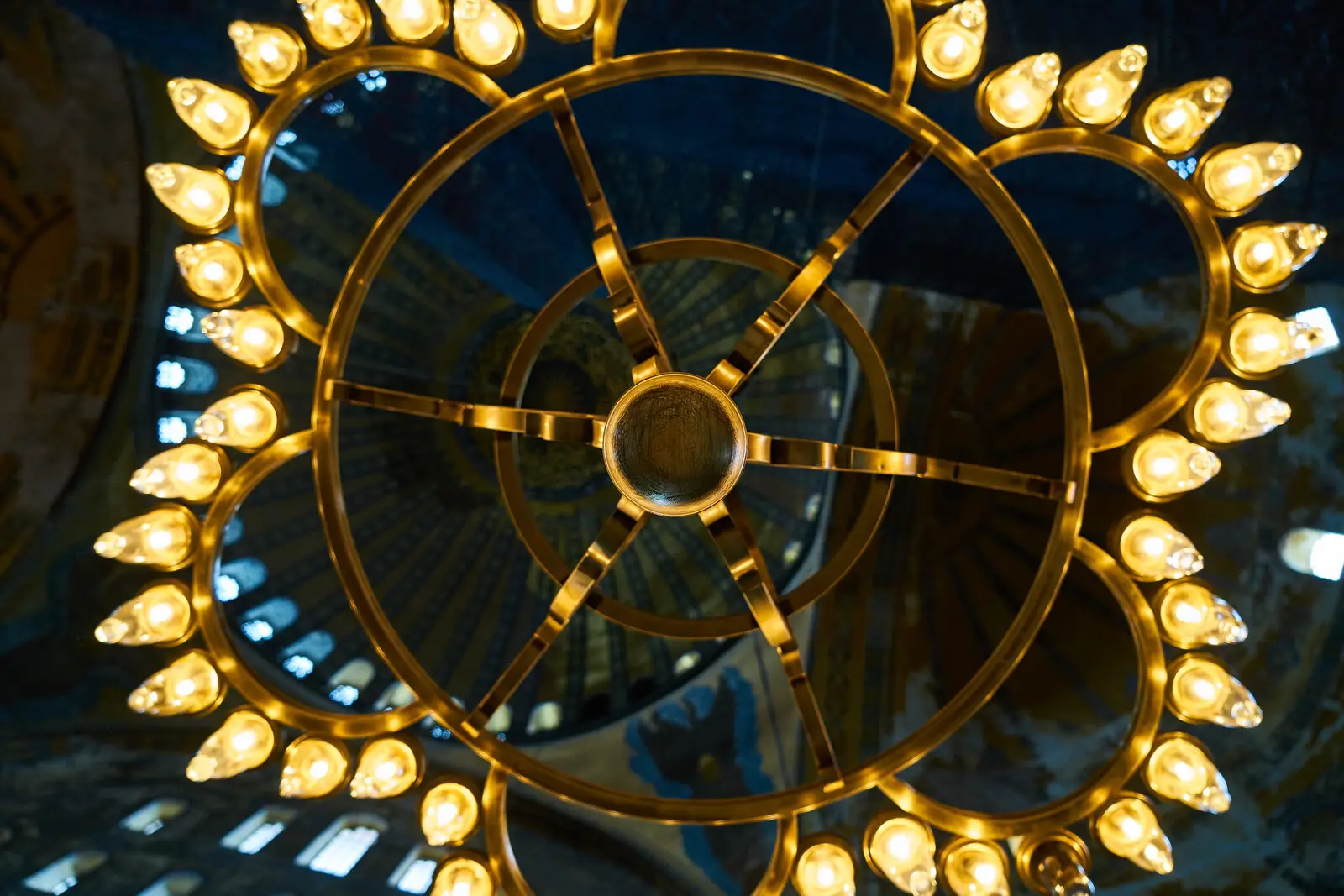 A close detail of ornate golden light bulbs arranged in a ring against a dark background, representing the small design details that build an immersive environment
