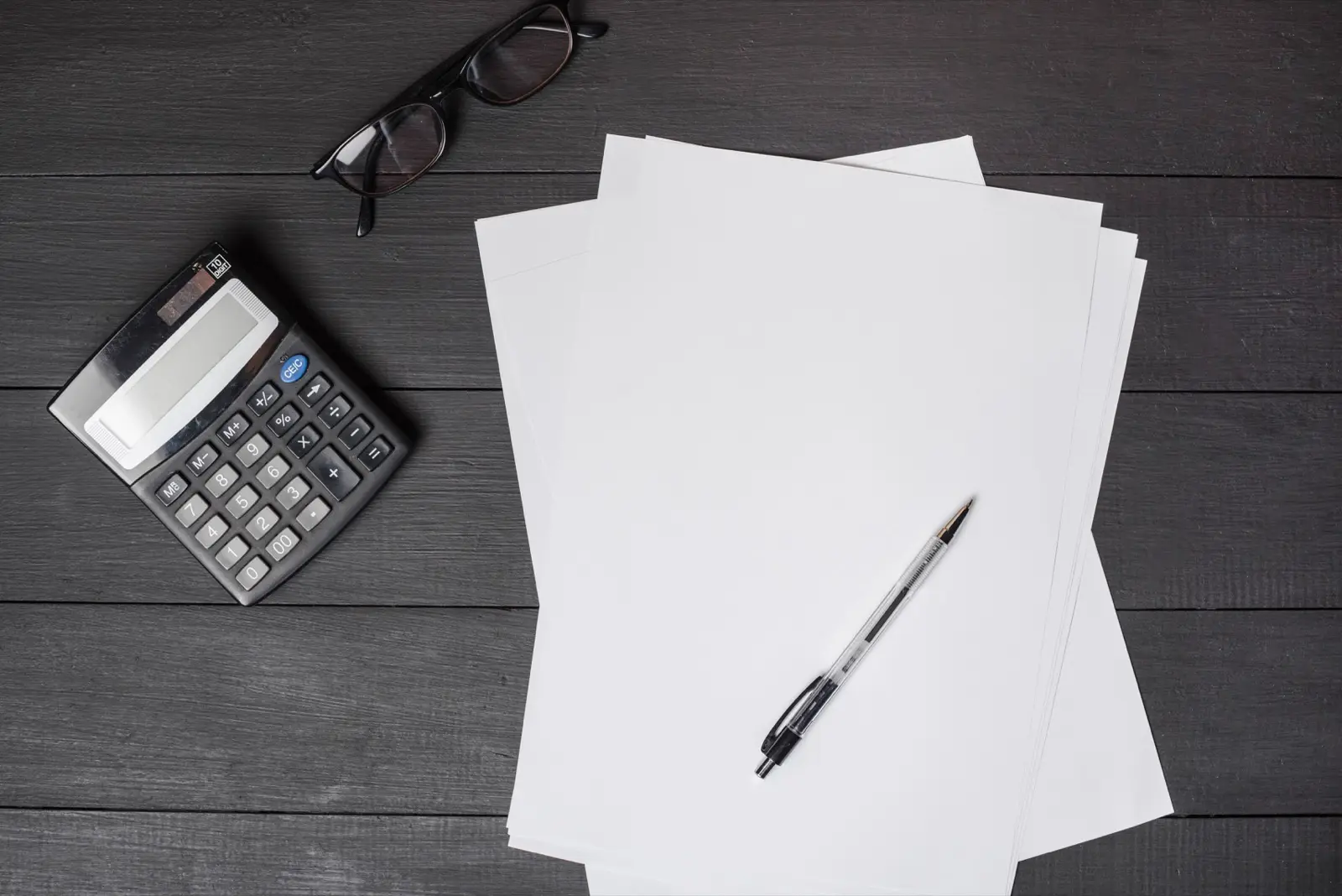 Two stacked paper documents beside a calculator and pen, representing comparing two website design quotes side by side